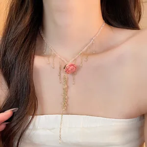 Primo piano di una collana con ciondolo a rosa rosa e eleganti catene a nappa d'oro