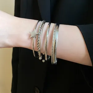 Set of silver vintage bangles featuring a star charm and textured bands on a wrist.