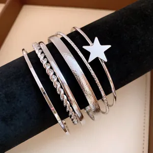 Macro view of a 6-piece silver star bangle set with textured and twisted designs.