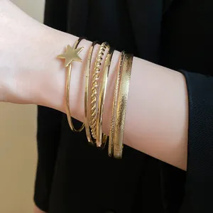 Close-up of five stylish gold-tone bangles including a star charm and twisted metal design