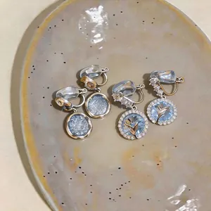 Dettaglio orecchini a clip blu cielo stellato e fiori in stile francese su piatto