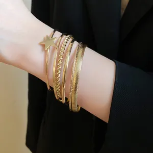Detailed shot of retro gold bracelet set featuring star charm and twisted textures