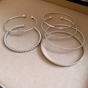 Detail view of silver-toned metal bracelets featuring star charm and twisted rope designs.
