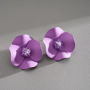 Macro view of elegant purple matte flower earrings with a square purple crystal center.