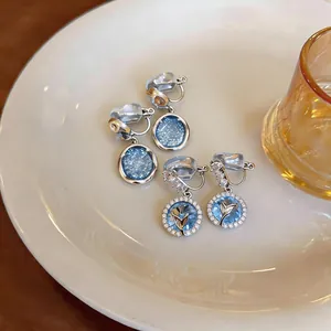 Dettaglio ravvicinato degli orecchini a clip francesi con cielo stellato blu e tulipano