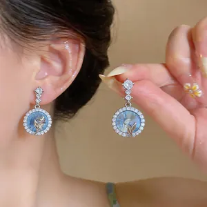 Primo piano di eleganti orecchini blu in stile francese con un alone di lucenti zirconi
