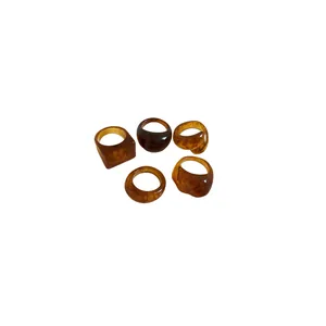 Set of five chunky resin rings in amber and brown tones with varied geometric designs