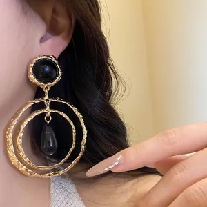 Close-up detail of vintage gold textured double hoops with black resin teardrop pendant