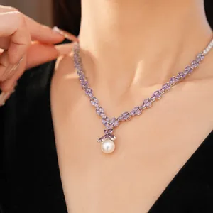 Detail of purple marquise zircon necklace with a dangling white pearl on a model