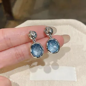 Primo piano di eleganti orecchini a clip blu cielo stellato con design in metallo