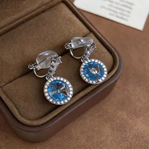 Dettaglio degli orecchini a clip blu stellato con motivo a coda di balena d'argento.