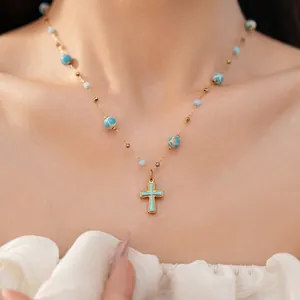 Turquoise beaded necklace with a vintage gold-toned cross pendant on a model
