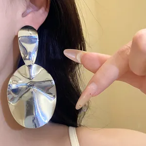 Detailed shot of large silver glossy oval earrings with a hammered metal texture