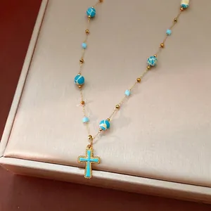 Elegant vintage gold chain necklace featuring blue enamel cross and patterned stone beads