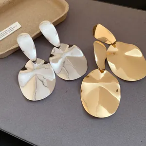 Detailed view of silver and gold metallic oval earrings with irregular textures