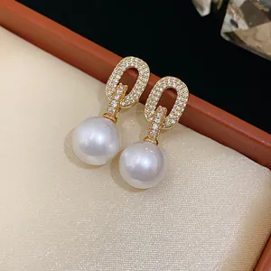 Close-up of elegant gold zircon oval earrings with large white pearl drops