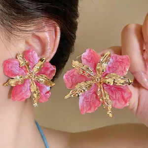 Detail of oversized pink wrinkled flower stud earrings with elegant gold metallic accents