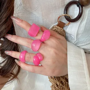 Detail showing vibrant pink candy resin rings in various chunky shapes on fingers.