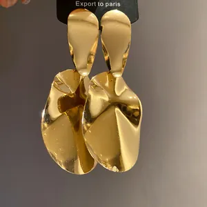 Detailed close-up view of geometric golden metal drop earrings with a glossy finish