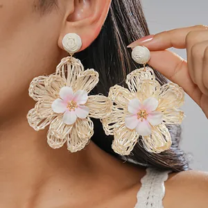 Detailed close-up of bohemian raffia hand-woven floral earrings worn by a model