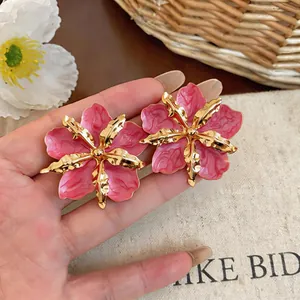 Close-up of elegant pink drip oil flower earrings featuring golden metallic petal details