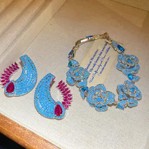 Dettaglio del bracciale floreale e orecchini a mezzaluna con zirconi blu e rosa