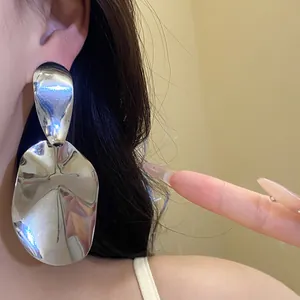 Oversized silver-tone glossy metal drop earrings with irregular oval shape
