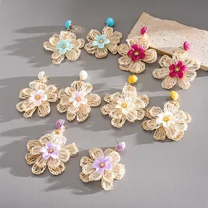 Close-up of hand-woven raffia flower earrings showing various vibrant colors for resort wear