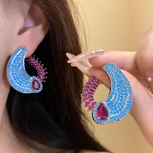 Dettaglio di orecchini a C con pavé blu e zircone rosa a goccia dall'aspetto lussuoso.