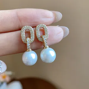 Detailed macro view of elegant gold-tone oval zircon stud earrings with white pearls