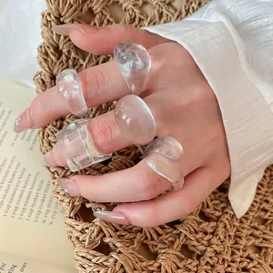 Close-up of trendy chunky clear resin rings set on a hand against a warm background