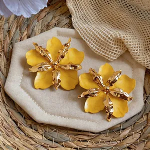 Close-up of large yellow flower stud earrings with gold metallic textured centers
