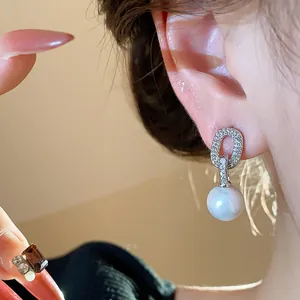 Close-up of elegant French style pearl earrings with zircon oval studs for women