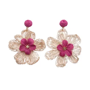 Handmade woven raffia flower earrings in bohemian holiday style with magenta petals.