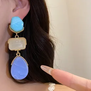 Boucles d'oreilles pendantes vintage en résine avec détails dorés sur modèle