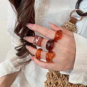 Close-up of amber-colored chunky resin ring set on fingers for trendy jewelry fashion