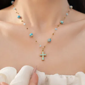 Detailed macro view of vintage gold cross necklace with turquoise enamel and stone beads