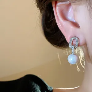 Detailed view of elegant oval zircon stud earrings with a dangling white pearl
