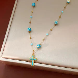 Close-up of a vintage gold necklace with turquoise oil drip cross pendant and beads