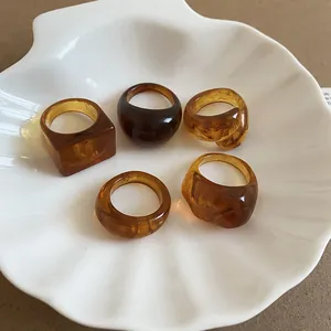 Detail view of five vintage amber resin rings with unique textures in shell dish