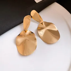 Detailed view of large gold-tone irregular oval drop earrings with a wavy texture