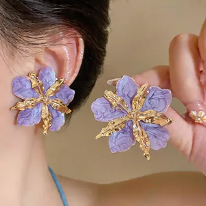 Close-up of purple wrinkled flower earrings with gold metal center and trendy style