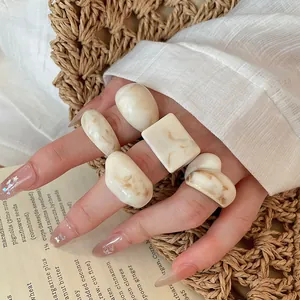 Close-up shot of trendy chunky cream resin ring set with marble texture on hand