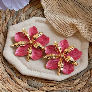 Detail of pink marble-textured oil-dripping flower earrings with golden metallic petals