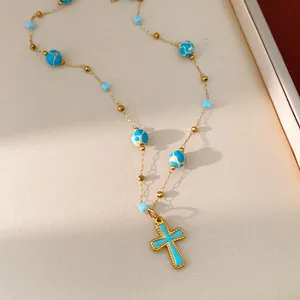 Close-up of blue enamel cross necklace with turquoise patterned beads on tray.