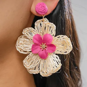 Detailed view of bohemian handmade raffia woven flower earrings on a female model's ear