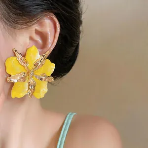 Close-up of bold yellow and gold crumpled flower statement earring on a model's ear.