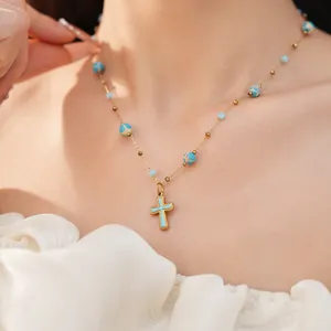 Macro detail of a vintage style beaded cross necklace with turquoise stones on a neck.