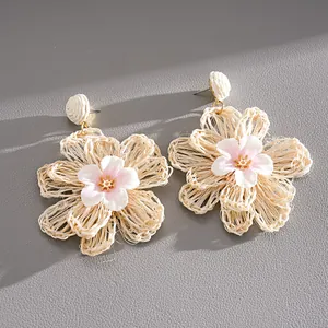 Detailed shot of raffia hand-woven floral earrings with delicate fabric flower center