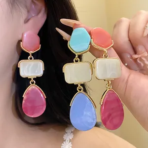 Gros plan de boucles d'oreilles pendantes en résine style vintage avec monture dorée.